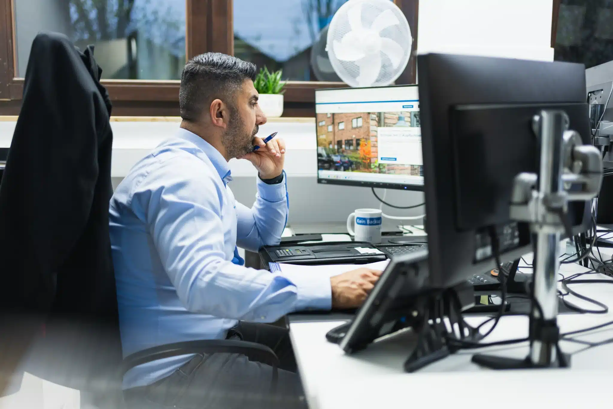 IT-Experte arbeitet konzentriert am Schreibtisch vor zwei Monitoren in einem modernen Büro